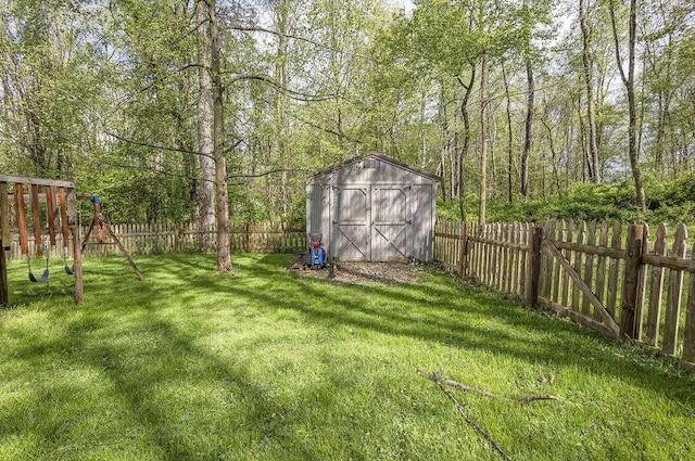 view of yard with a playground, an outbuilding, a fenced backyard, and a shed