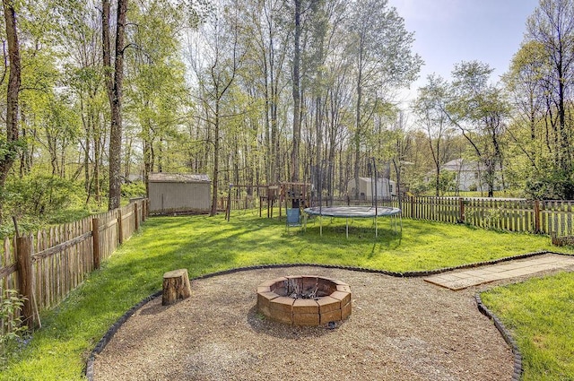 view of yard with a trampoline, a fire pit, and a fenced backyard