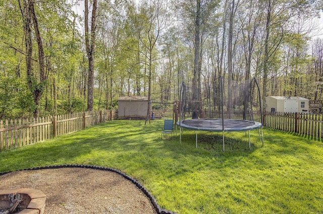 view of yard with a fenced backyard, an outdoor structure, a trampoline, and a shed