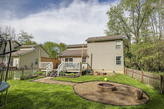 back of property with an outdoor fire pit, a yard, a deck, and fence