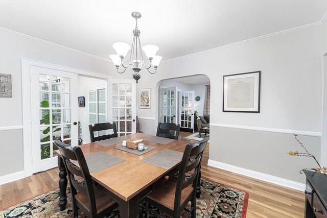 2842 Powell Ave, Columbus, OH 43209 - dining room featuring arched walkways, a chandelier, light wood-style flooring, ornamental molding, and baseboards