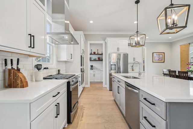 kitchen with island exhaust hood, appliances with stainless steel finishes, a chandelier, a sink, and tasteful backsplash