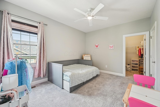 carpeted bedroom with a spacious closet, baseboards, a ceiling fan, and a closet