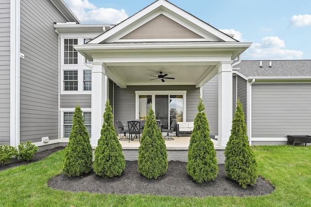 entrance to property featuring ceiling fan, a lawn, and an outdoor living space