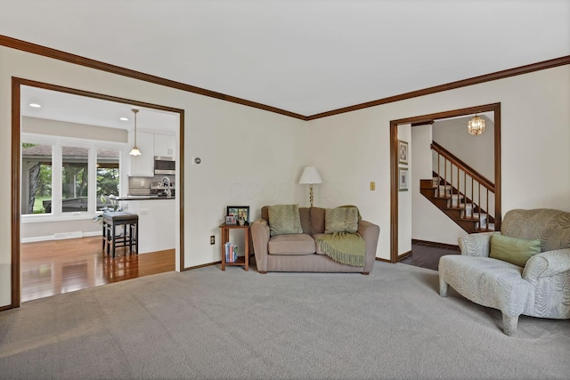 living room featuring stairway, crown molding, and carpet flooring