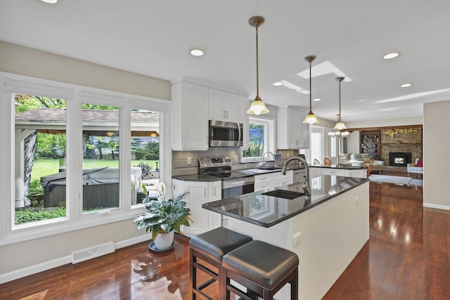kitchen with stainless steel appliances, visible vents, a sink, and dark wood-type flooring