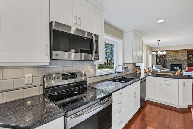 kitchen with an inviting chandelier, a sink, stainless steel appliances, white cabinets, and backsplash