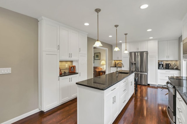 kitchen with a sink, dark wood finished floors, appliances with stainless steel finishes, tasteful backsplash, and recessed lighting
