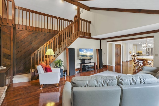 living room with stairs, hardwood / wood-style floors, an inviting chandelier, and high vaulted ceiling
