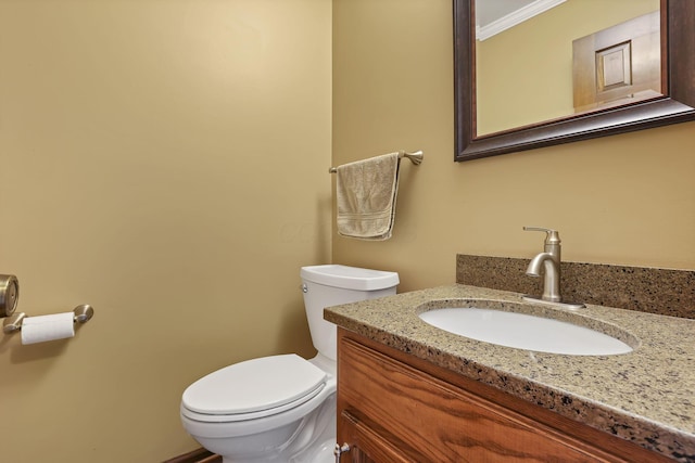 bathroom with toilet, vanity, and ornamental molding