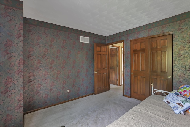 bedroom with wallpapered walls, visible vents, and carpet floors
