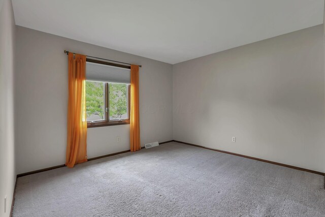 carpeted empty room featuring baseboards and visible vents