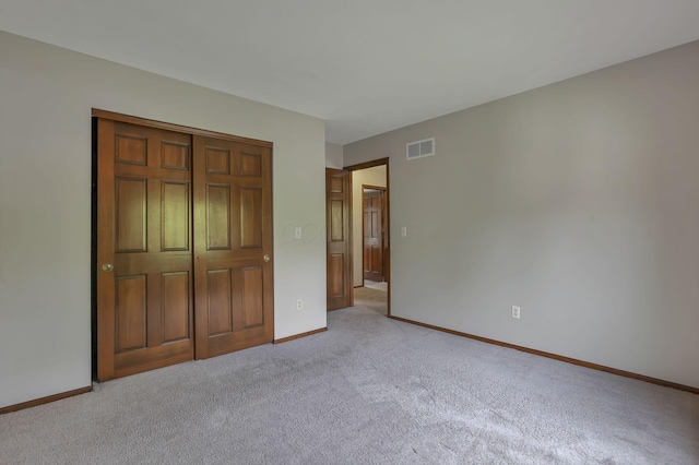 unfurnished bedroom featuring light colored carpet, baseboards, a closet, and visible vents