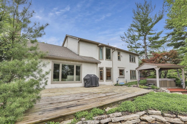 rear view of property featuring a hot tub, a wooden deck, and stucco siding