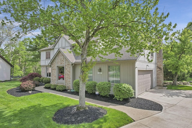 english style home featuring a garage, a front yard, a shingled roof, and driveway