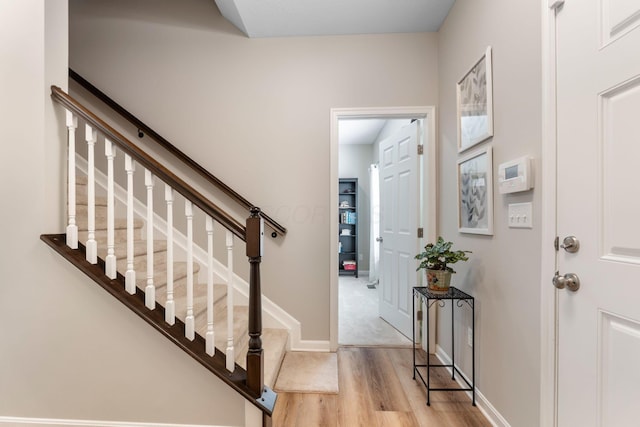 foyer featuring wood finished floors, stairway, and baseboards