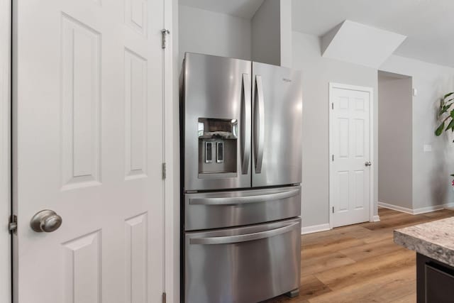 kitchen featuring stainless steel fridge with ice dispenser, light wood finished floors, baseboards, and light countertops