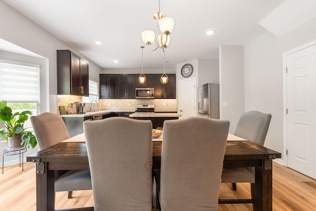 dining area with light wood-style floors, recessed lighting, and a chandelier