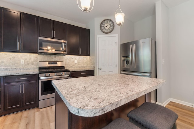 kitchen with stainless steel appliances, light countertops, backsplash, light wood-type flooring, and dark brown cabinetry