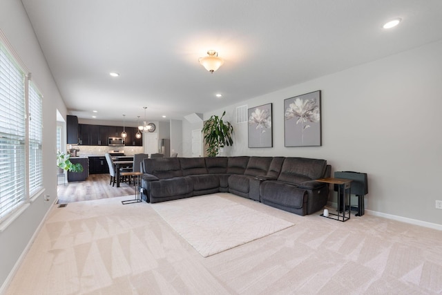 living area with light colored carpet, recessed lighting, baseboards, and a chandelier