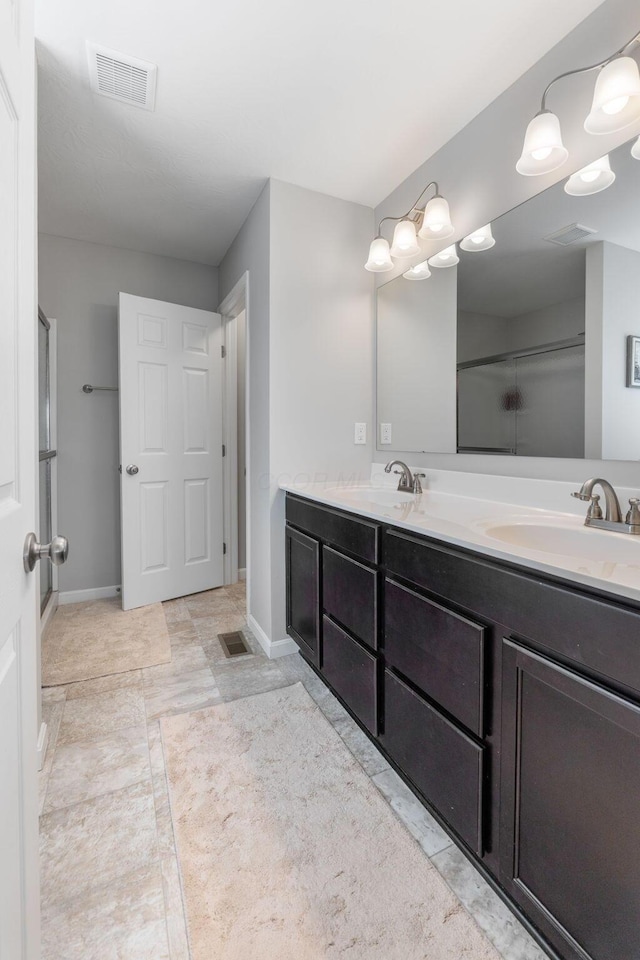 bathroom with double vanity, a shower with shower door, and baseboards