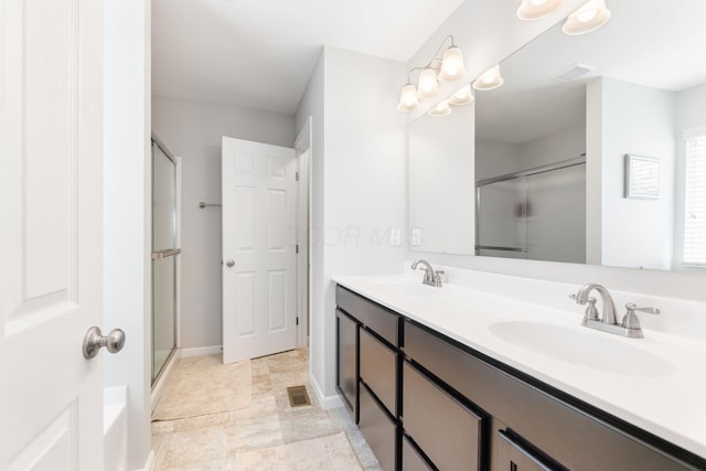 bathroom featuring a shower stall, double vanity, and baseboards