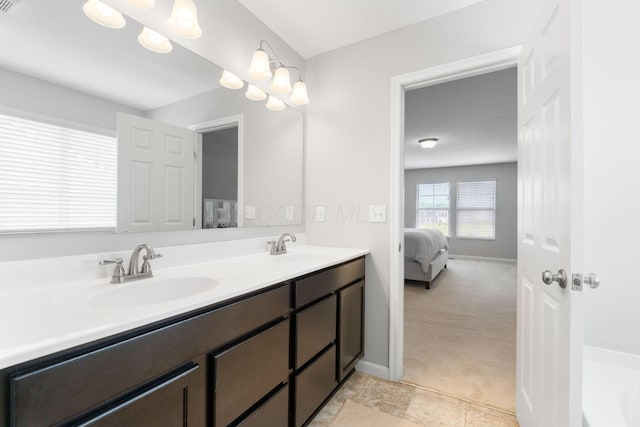 ensuite bathroom featuring double vanity, a tub to relax in, and baseboards