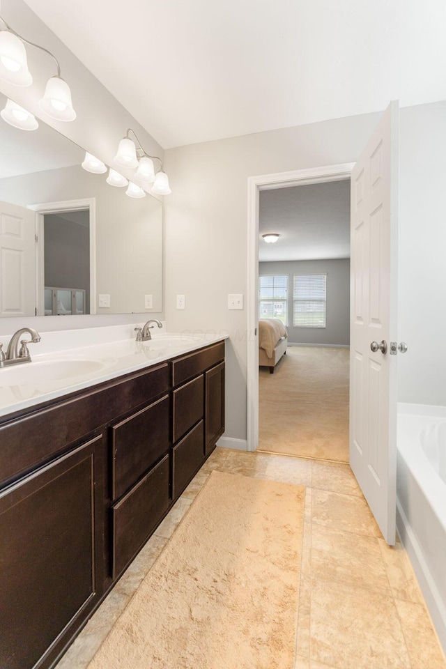 ensuite bathroom with double vanity, a tub to relax in, and tile patterned floors