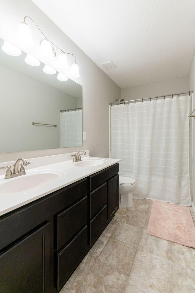 bathroom with double vanity and toilet
