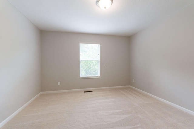spare room with light carpet and baseboards