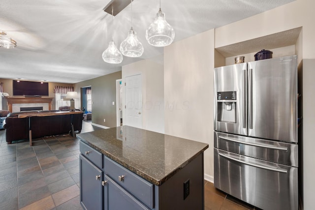 670 Mill Wood Blvd, Marysville, OH 43040 - kitchen with stainless steel refrigerator with ice dispenser, a kitchen island, hanging light fixtures, blue cabinetry, and dark stone counters