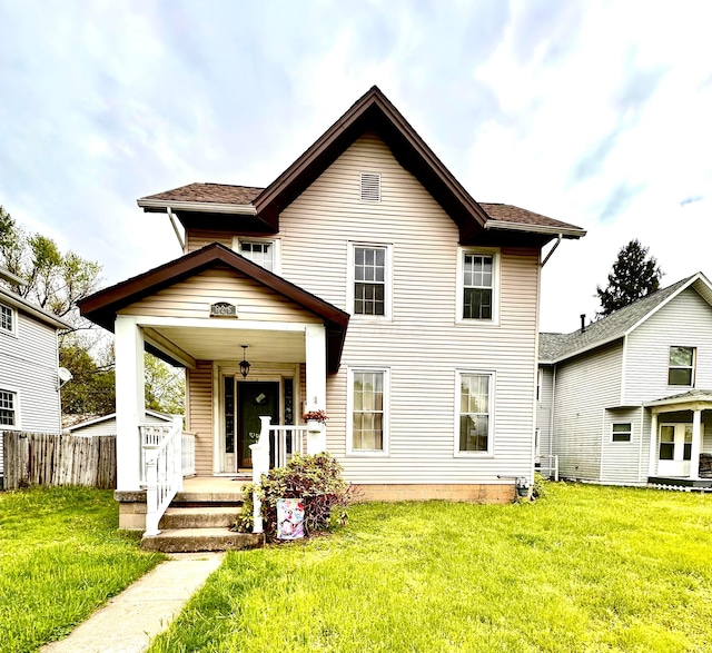 traditional home featuring a porch, a front lawn, and fence