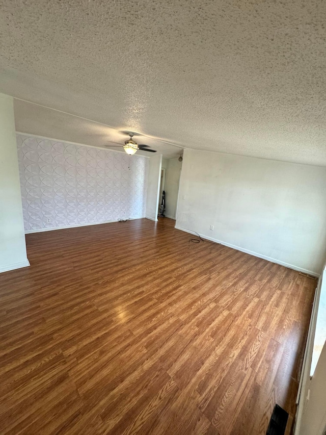 empty room with baseboards, a textured ceiling, and wood finished floors
