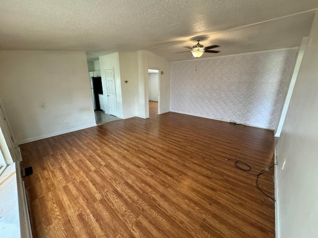 spare room with a textured ceiling, wood finished floors, baseboards, and ceiling fan