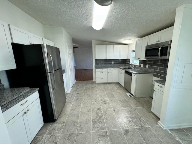 kitchen with a textured ceiling, appliances with stainless steel finishes, white cabinetry, and a sink