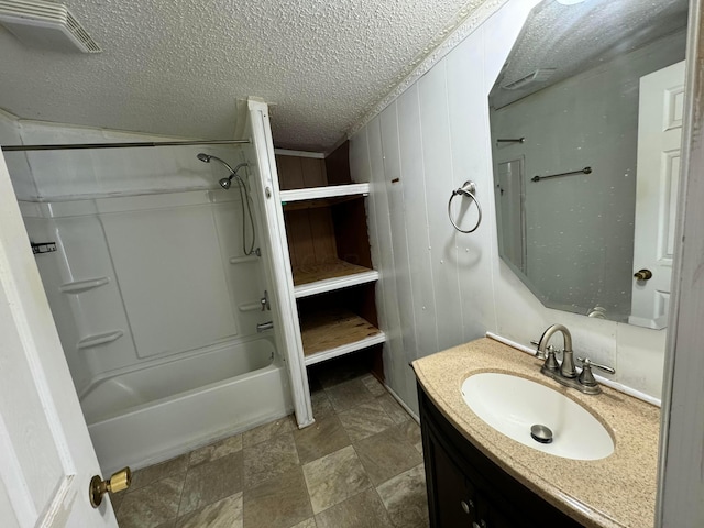 bathroom featuring vanity, a textured ceiling, stone finish floor, visible vents, and tub / shower combination