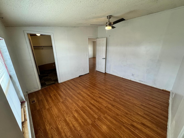 unfurnished bedroom with wood finished floors, a ceiling fan, a textured ceiling, visible vents, and baseboards
