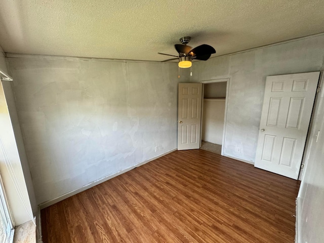 unfurnished bedroom featuring a closet, wood finished floors, a textured ceiling, a ceiling fan, and baseboards