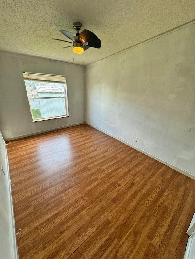 unfurnished room with ceiling fan, a textured ceiling, and wood finished floors