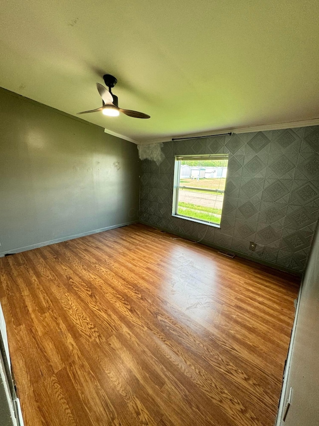 empty room with crown molding, ceiling fan, and wood finished floors