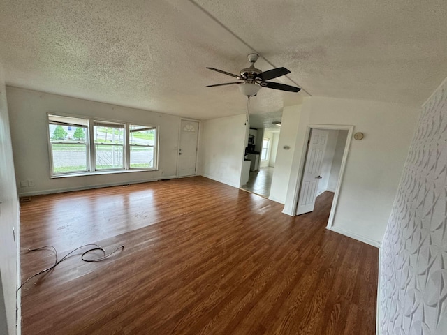 unfurnished living room with ceiling fan, a textured ceiling, baseboards, and wood finished floors