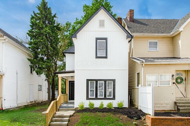 view of front facade featuring a chimney, board and batten siding, fence, a shingled roof, and a front lawn