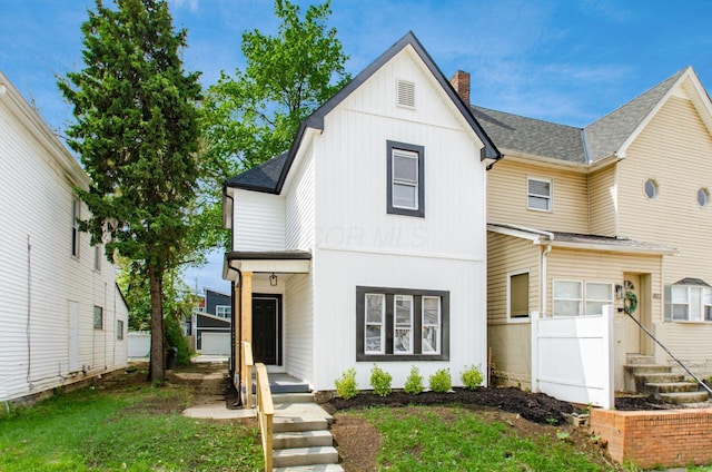 modern farmhouse style home featuring a chimney, board and batten siding, and roof with shingles