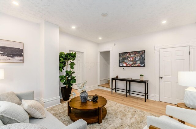 living room featuring baseboards, light wood-style floors, and recessed lighting