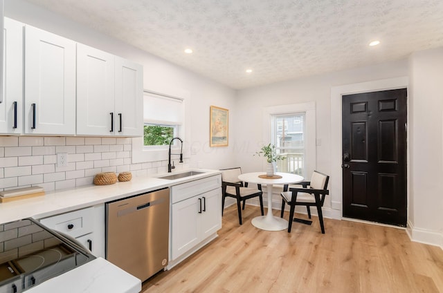 kitchen with stainless steel dishwasher, a textured ceiling, plenty of natural light, and a sink