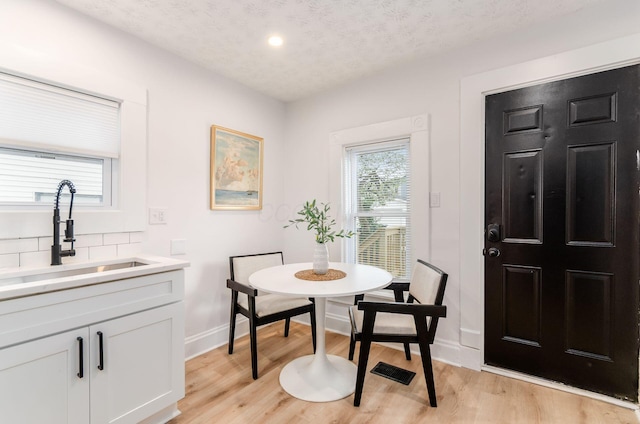 dining area featuring recessed lighting, light wood-type flooring, baseboards, and a textured ceiling