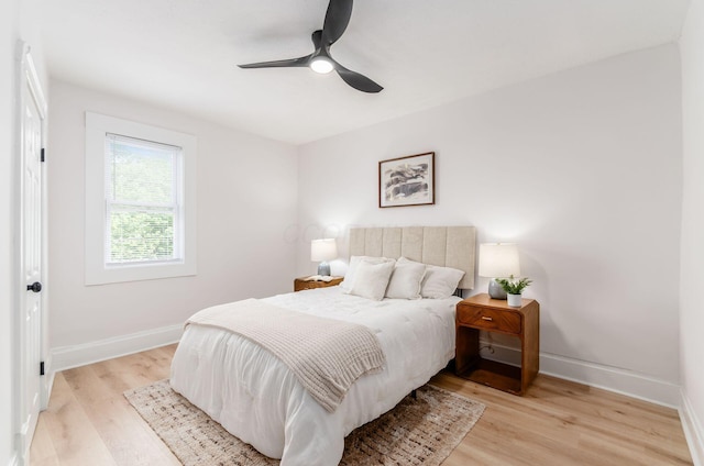 bedroom with ceiling fan, light wood-style flooring, and baseboards