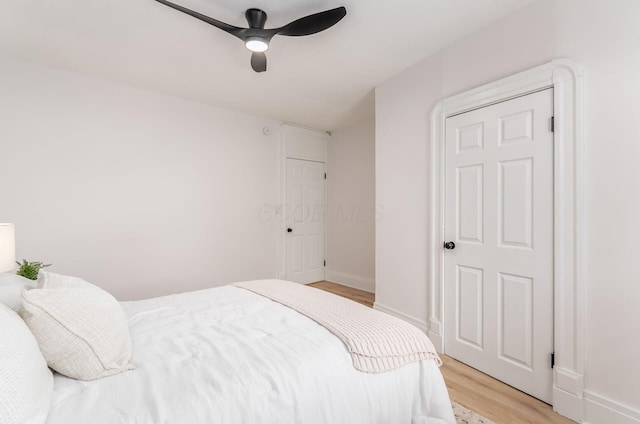 bedroom with light wood finished floors, baseboards, and ceiling fan