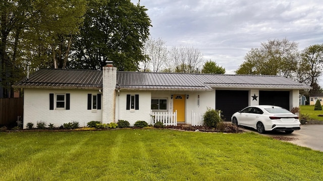 ranch-style home with an attached garage, metal roof, a front lawn, a chimney, and a standing seam roof