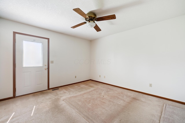 empty room with baseboards, visible vents, and light colored carpet